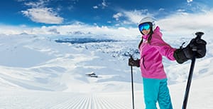 happy young woman on skis at the top of a beatifully groomed piste
